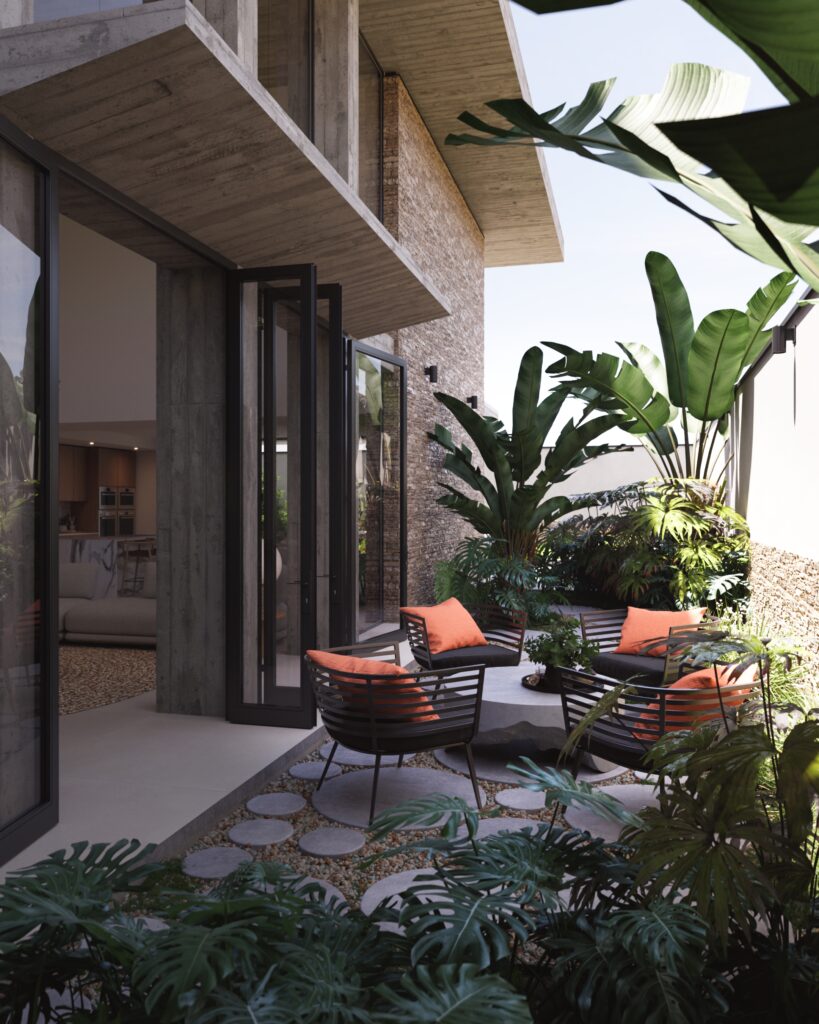Conexión de la zona social con el jardín lateral mediante suelos de piedra y diseño de paisaje.